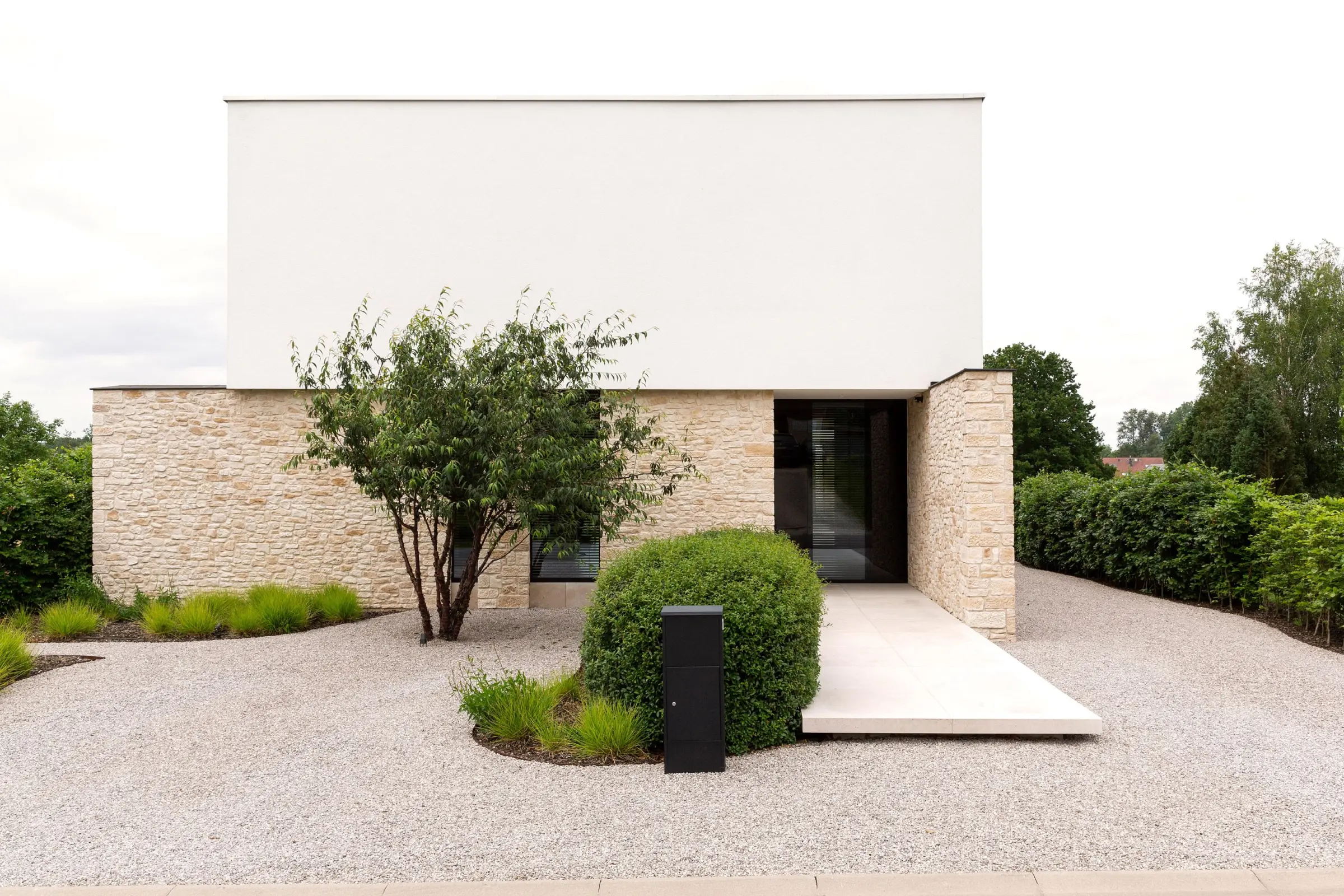 Woning witte sierpleister Sto en beige stenen