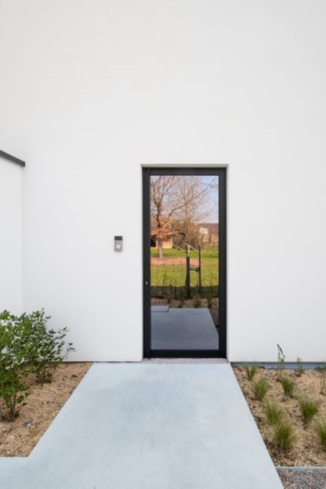 Porte d'entrée moderne en verre et façade en crépis blanc