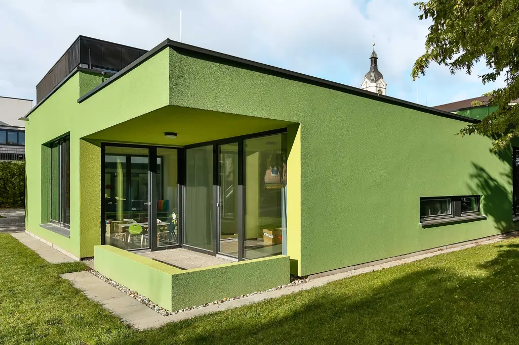 Buitenzijde van een kinderdagverblijf, groene gevel, geïsoleerd met het houtvezel ETICS-systeem 