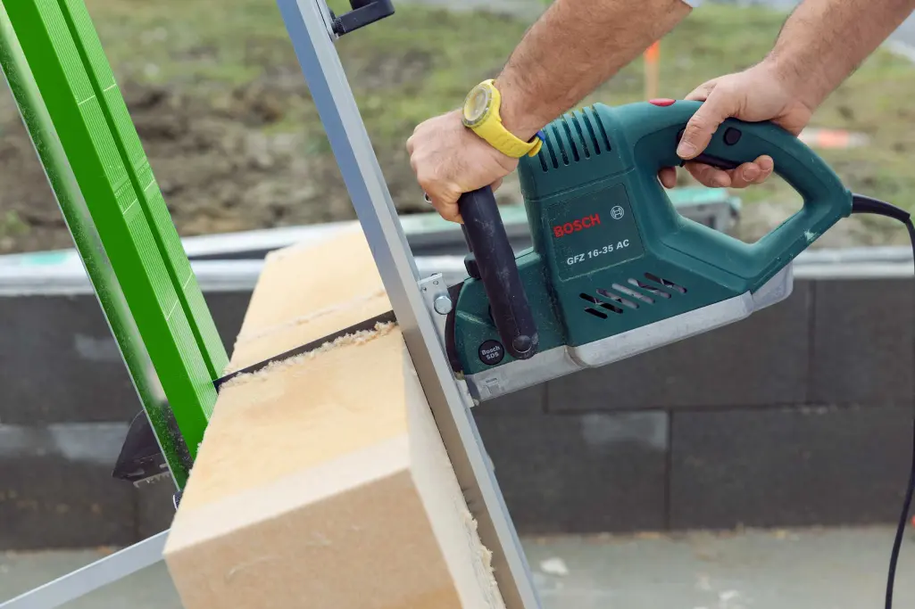 Foto van de applicatie. Een vakman zaagt een Sto-houtvezelpaneel op maat.